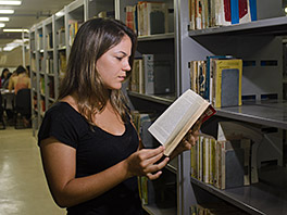 Mulher lendo livro na biblioteca